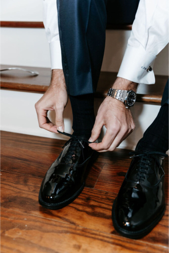 groom putting on his shoes at seaside wedding